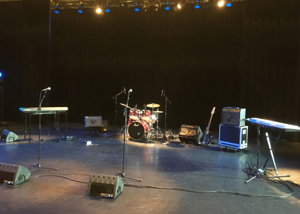 Een afbeelding van een podium met backline en podiumverlichting
